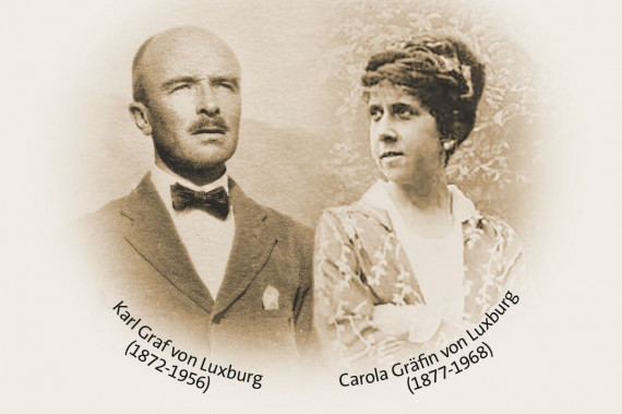 Das Foto ist sehr alt und in braunen Farben. Auf dem Foto sind zwei Porträts. Rechts ist Gräfin Carola mit hochgesteckten Haaren. Darunter stehen ihre Lebensdaten: 1877 bis 1968. Links ist Graf Karl. Er hat einen kleinen Schnurrbart. Darunter stehen seine Lebensdaten: 1872 bis 1956.