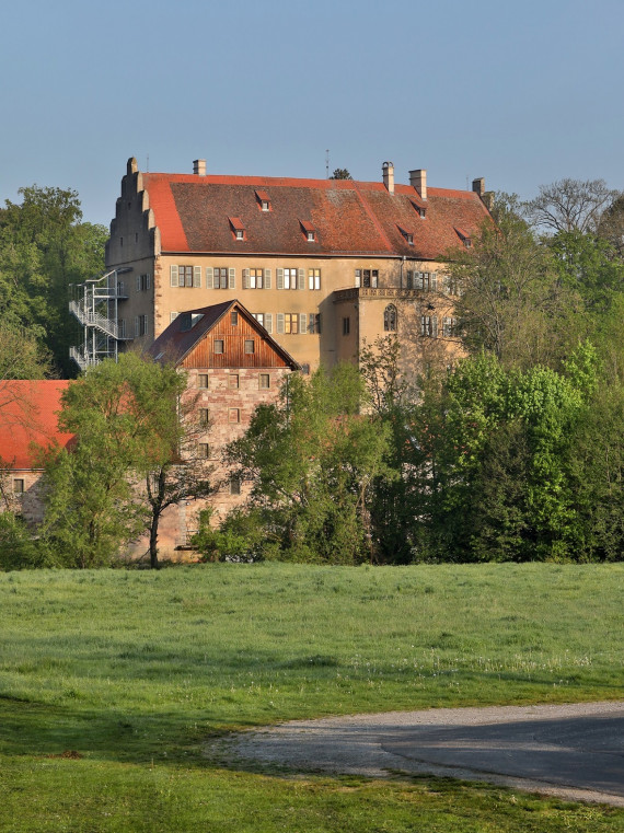 Auf dem Foto sind mehrere große Gebäude. Zusammen bilden die Gebäude das Schloss Aschach.